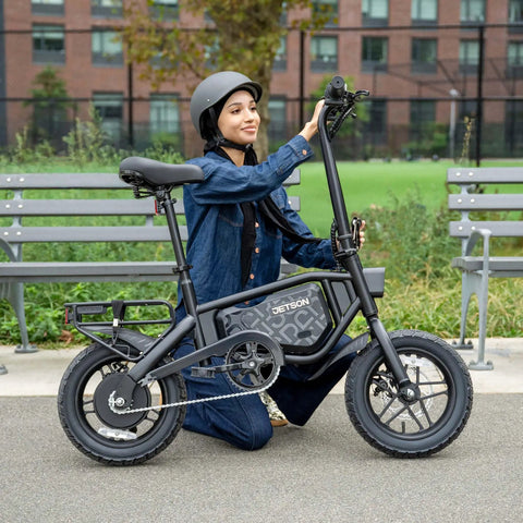 Person sitting near Foldable Electric Bike With Carry Handles Portable 350W Pedal Assist Twist Throttle Up To 15.5 MPH 14 Inch Tires