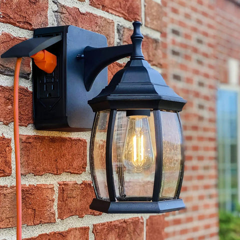 Traditional Outdoor Wall Sconce With Seeded Glass And Two Built In GFCI Outlets For Easy Access Power Black Finish Weather Resistant Porch Lighting For Patio Or Garden mounted on brick wall.