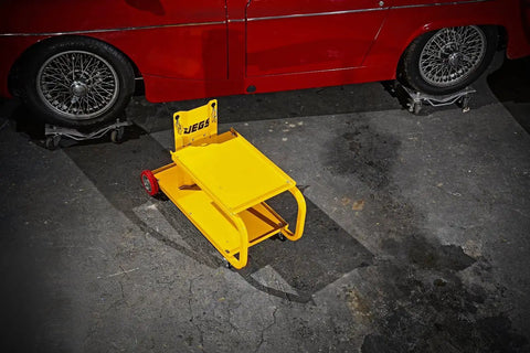 HEAVY DUTY YELLOW POWDER COATED STEEL WELDING CART WITH SMOOTH ROLLING CASTERS AND SLANTED WORK SURFACE BUILT TO CRUSH THE GRIND AND HAUL YOUR GEAR FAST on a garage floor next to a classic car.