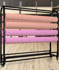 Hella Sturdy Fabric Roll Storage Rack With Smooth Riding Casters And Adjustable Hanging Rod Display Shelf For Leather Wallpaper Rolls showcasing four rolls of fabric.