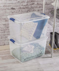 Heavy Duty SixtySix Quart Clear Plastic Storage Bins Two Pack With Blue Latch Lids showing stacked bins with pillows and blankets inside.
