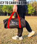 Person carrying a black and red sports bag on a grassy field