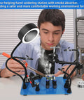 Young man using Magnetic Helping Hands Soldering Third Hand Tools With Pro Grade Lighted Solder Fume Extractor for electronics repair.