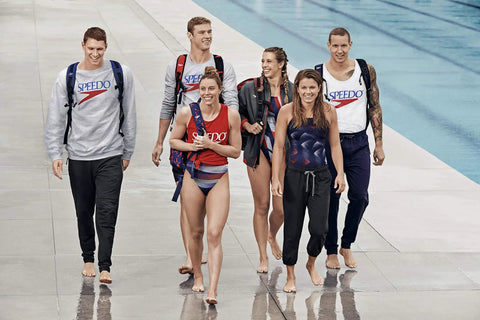 Group of swimmers with branded gear walking by the poolside