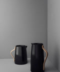 Two Emma Insulated Coffee Flask 1.2 Liter With Beechwood Handle, high-gloss black exterior, on a grey surface.