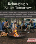 Group of campers around a fire with tents and chairs, outdoors with trees and a van in the background for a camping trip.