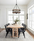Dining room with Dope Rustic Farmhouse 19 Inch Chandelier With Wood And Black Metal Arms, over light wood table and black chairs.