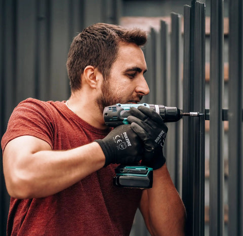 Man wearing Ultra Thin PU Coated Work Gloves 12 Pairs With Nylon Knit Shell And Knit Wrist Cuff for light duty jobs using drill