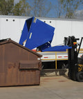 Solid Workhorse Steel Self Dumping Hopper For Forklift 3 Cubic Yard 2000 Lb Payload Capacity in use at a loading dock.