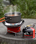 Isobutane Camping Stove Fuel Canister 230 Gram Butane Propane Blend beside a stove with cooking pot outdoors