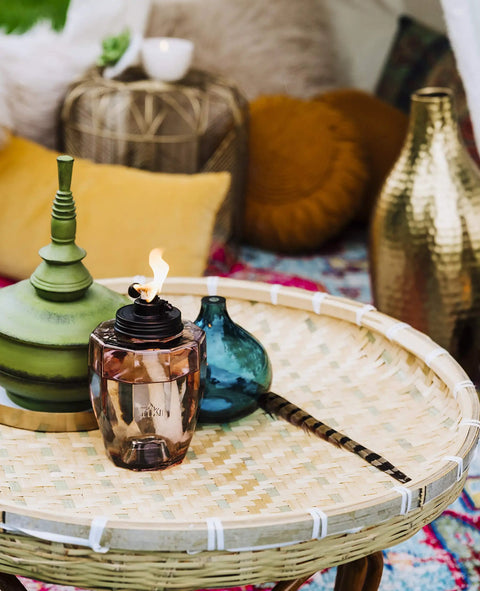 Adjustable Flame Glass Torch For Outdoor Decor Pink on woven table with decorative elements