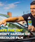 Top Shelf Foaming Auto Glass Cleaner Blast Away Road Grime And Bird Droppings From Windshield And Windows Without Leaving Streaks Or Smudges For A Flawless Shine Every Time 19 Ounce Spray Pack Of 2 being used to clean a tinted car window.