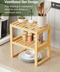 Heavy Duty Bamboo Cabinet Organizer Shelf Two Pack Stackable Kitchen Counter Rack Featuring Slatted Draining Surface To Air Out Dishes And Keep Counters Squeaky Clean. Two tier bamboo rack with slatted design, holding plates and jars.