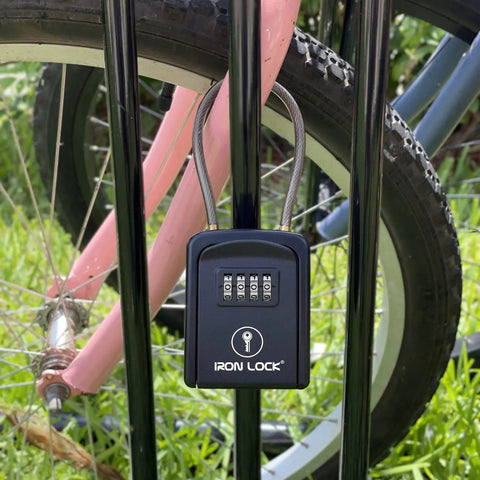 Rugged Outdoor Key Lock Box With Cable Shackle, Small Waterproof Metal Safe, 4 Digit Combo For Spare Keys on fence with bike