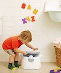 A toddler interacting with The Real Deal Toddler Potty Training Chair 3-In-1 Potty Seat With Step Stool Plus Arm And Hammer Deodorizing Disc Gray.