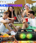 Group enjoying Party-Ready 120W Bluetooth Speaker With IPX6 Waterproof Build at outdoor event with LED lights and karaoke mode.