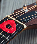 Axe Blade Medium Guitar Picks With Smooth Edge on a guitar neck, showing ergonomic grip, versatile 3 sided tip, red color.