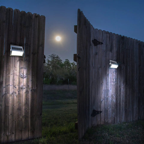 Upgrade Solar Step Lights 12 Pack Outdoor LED Deck Lights With Side Button Design illuminating wooden fence at night