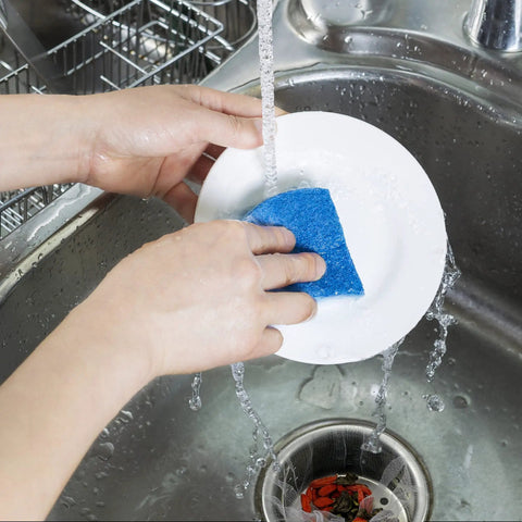 Person washing a plate in a sink using blue sponge above 500 Pcs Disposable Mesh Sink Strainer Bags Elastic Kitchen Filter Mesh Trash Bags Anti Clog Fits Most Strainer Sizes 3.9 x 4.3 Inch Keeps Your Sink Fresh And Odor Free For Quick No Mess Cleanups