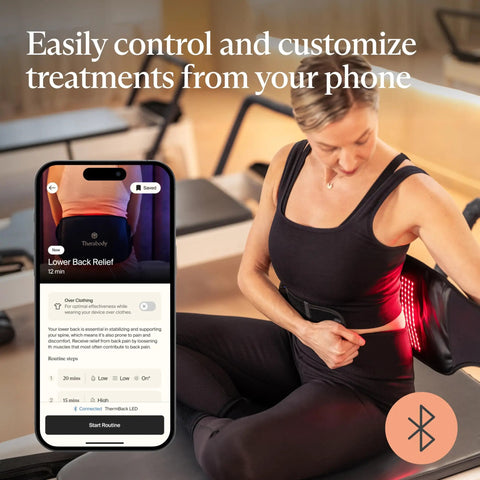 Woman using Four In One Back Wrap With Heat, Far Infrared, Vibration, And LED Therapy for epic lower back pain relief at home with phone app