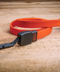 36 Inch Flat Bungee Straps 2 Pack With Coated Steel Hooks And Easy Grip Pad Black And Orange laying on wood surface