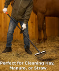 Person using Heavy Duty Metal Horse Manure Fork With Long Steel Handle Built Tough Two Pack Poop Shovel Rake on stall floor
