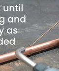 Close-up of welding glove holding 1/16 Inch ER70S-6 Mild Steel TIG Filler Rod, 1 Lb Pack for welding mild steel, with torch and copper pipe