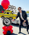 Route 66 Retro Party Balloons Kit With Vintage Car Tire Decor And Vinyl Record Foil Balloons shown with person outdoors