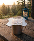 Total Game Changer Metal Coffee Drip Assist Tool And Portable Pour Over Dripper Stand on a wooden table outdoors.