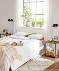 Bedroom scene with set of two industrial style end tables with rustic brown tops and matte black steel frames beside the bed.