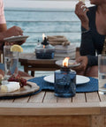 Blue Glass Tabletop Patio Torch Lights Set Of 3 Refillable Garden Lanterns for outdoor ambiance on patio table with food and drinks.