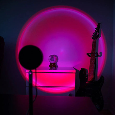 Sunset Lamp With Remote LED RGB Projection Night Light casting multicolor sunset glow in a living room with guitar in the background.