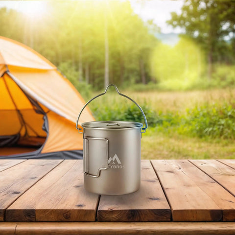 Pure Titanium 750ml Camping Pot With Spork Kit For Solo Backpacking on a wooden table near a tent, ideal for outdoor cooking.