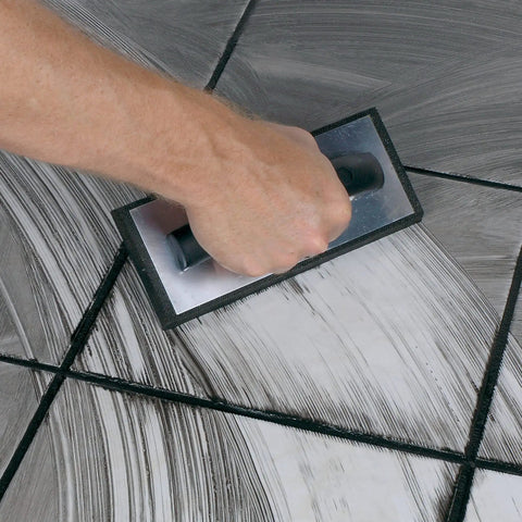 Hand using Molded Rubber Grout Float With Non Stick Gum Rubber Pad 4 In By 9.5 In Aluminum Back Plate Beveled Sides For Smooth Tile Grout Application