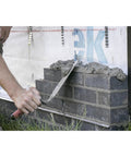 Worker using London Style Pro Grade Brick Trowel With DuraSoft Handle For Brickwork Blockwork And Stonework Ten And One Half Inch By Four And Three Quarters Inch Forged High Carbon Steel Made In USA Masonry Tool on brick wall