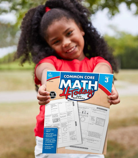Child holding Common Core Math 4 Today 3rd Grade Workbook For Daily Practice In Class Or Homeschool outside