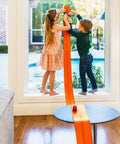 Two children playing with Flexible 15 Foot Race Car Track For Kids With Suction Cups Rolls Up Portable Racetrack on window.