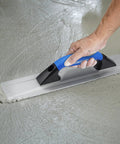 Hand using Pro Grade Cast Magnesium Concrete Hand Float With Ergonomic Rubber Handle 16 By 3 And A Half Inches Widened Beveled End For Smooth Finishes Curved Base Mag Trowel on wet concrete surface.