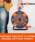 Man holding 60 Ft Cord Reel With Four Outlets 14 AWG SJTW Cable Workhorse, orange and grey design, Link2Home logo visible.