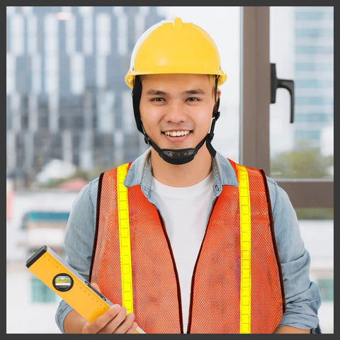 Man wearing Neon Orange 20 Pack High Visibility Reflective Safety Vest with Lightweight Mesh and yellow hard hat at construction site.