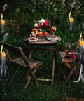 Outdoor dining scene with Citronella Torches 6 Pack for Outdoor Lighting, 60 Inch Jet Black Metal Pathway Torches, flickering flame