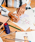 Designer using a T Shirt Alignment Ruler Kit For Vinyl Designs 4 Piece PVC Ruler Set with sketches and tools on a desk
