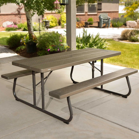 Six Foot Folding Picnic Table With Classic Rugged Steel Frame Seats Eight UV Protected Top Weather And Rust Resistant Flat Fold For Easy Stow And An Umbrella Hole For Backyard Hangouts in a garden setting.