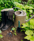 Gardening tools including Three Tine Hand Garden Fork With Aluminum Alloy Non Slip Handle next to a watering can and boots
