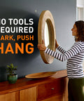 Woman using heavy duty drywall picture hanger that holds up to 65 pounds; installs in seconds with a quick push; no tools required