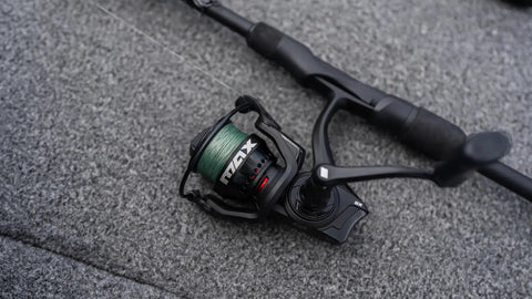 6 Ft 6 In Max SX Spinning Rod And Reel Combo Size 3000 with green line on a boat surface, featuring 7 stainless steel ball bearings.