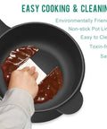 Hand wiping nonstick 2L Mini Electric Pot with Sauté and Steam Function, highlighting easy cleaning feature, black interior.