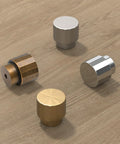 Various metal cabinet knobs on wooden surface; includes Antique Brass Round Cabinet Knobs 1.1 Inch Diameter Zinc Alloy With Brushed Finish.