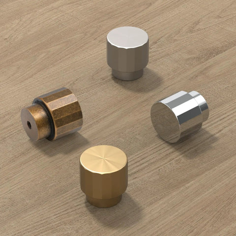 Various metal cabinet knobs on wooden surface; includes Antique Brass Round Cabinet Knobs 1.1 Inch Diameter Zinc Alloy With Brushed Finish.