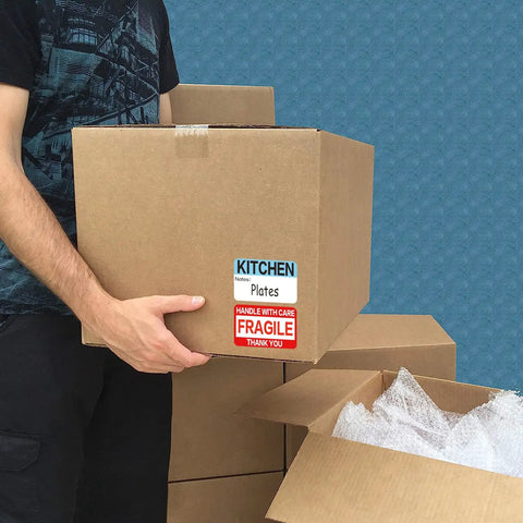 Person holding box with Massive 600 Count Moving Box Labels Pack For Three To Four Bedroom Homes With Writable Note Areas.